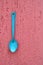 Rustic metalic blue spoon on a pink wall