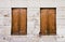 Rustic old grungy and weathered brown wooden closed windows shutters with peeling paint on a white cracked wall