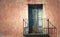 Rustic old grungy and weathered wooden closed door of rusty balcony with a red brown vintage cracked wall