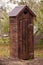 A rustic open toilet is in the garden. Rural lifestyle, latrine, toilet, outhouse, architecture, nature, garden, old, rustic,