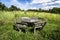 Rustic picnic bench in uncultivated meadow with blue sky