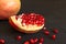 Rustic piece of pomegranate fruit on black table close up with s