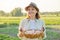 Rustic portrait of mature woman with basket of eggs at meadow