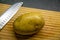 Rustic potato on a wooden chopping board with silver stainless steal knife for cutting