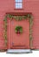 Rustic red barn with boughs of fir trees decorating front entrance and pretty wreath on door