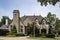 Rustic rock and brick upscale beautifully landscaped home with copper spires and chimney covers flying American flag on tall flagp