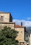 Rustic rock building in seaside Greek village with terra cotta roof tiles and a metal bird fastened onto the metal stove pipe -