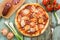 Rustic round pizza with salami. Cherry tomatoes, salami, garlic, leek and fork on background