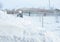 Rustic scarecrow, snow-covered fence, large snowdrift after a blizzard or storm, village landscape