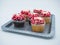 Rustic silver tray at an angle, filled with chocolate and vanilla cupcakes decorated for Valentineâ€™s Day with white frosting and