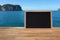 Rustic slate menu blackboard on wooden desk and sea view blur ba