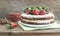 Rustic spicy ginger cake with cream-cheese filling and fresh strawberries with a rough wood background