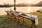 Rustic style dining table with flower, wine glass, candle decoration at dinner by the river in the sunset