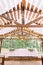 Rustic tent restaurant with wedding or dinner table and floral decorations and light bulbs, on a background of green