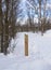 Rustic trail indicator post in snowy landscape on the polar circle. Solid wooden post in the middle of the snow. Signaling of