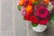 Rustic wedding bouquet with orange, crimson and bordeaux roses, poppy and other flowers and greens on the blurred wooden