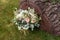 rustic wedding bouquet with roses and other flowers on green grass and wooden texture