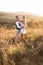 Rustic wedding and love story concept. Boho ypsy woman and man posing in summer field, hugging and looking each other