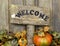 Rustic welcome sign with autumn leaves and pumpkin border