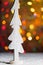 Rustic white wooden tree decoration standing in snow, with christmas tree lights