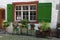 Rustic window with green shutters and flower pots