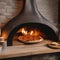 A rustic wood-fired pizza oven with flames flickering and a pizza inside4