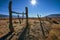 Rustic wood and wire fence in arid valley with distant snowy mountains