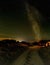 Rustic wooden cabin in a grassy meadow under a starry night sky