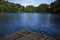 Rustic wooden raft on still water lake. Idyllic lake crossing with old raft. Summer travel to mountain camp.