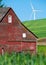 Rustic wooden red barn with modern wind turbines in the background