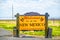 Rustic wooden roadside sign - Welcome to New Mexico Land of Enchantment with rolling irrigation system blurred in field behind