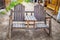 Rustic wooden seat for two with table built in middle of bench and arm rests and backs sitting on dirt in alleyway with porches