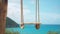 A rustic wooden swing on ropes against a tropical teal blue ocean horizon seascape illustration.