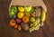 A rustic wooden table with a paper bag full of lots of freshly picked fresh fruit. Many vitamins together on a wooden table