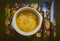 Rustic yello wsoup pn a flowery table mat with knife and spoon