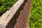 Rusticated stone cap on a red brick retaining wall, abundant greenery