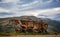 Rusting and decaying combine harvester abandoned on mountain roadside with dramatic mountains behind