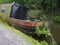 Rusting houseboat overgrown with weeds moored on the rochdale canal listing to one side and beginning to sink