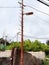 Rusty abandoned lamp post. A rusty lamppost in a green village against the background of a concrete foundation of a