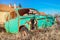 Rusty and abandoned retro Fiat 600 car in a junk yard against clear blue sky.