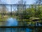 A rusty abandoned steel truss bridge over a small slow moving river.