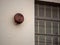 Rusty alarm bell hanging outside of large window outside school building