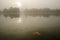 Rusty autumn leaf on a lake mirror, with misty background, in the morning light