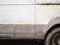 Rusty body of an old car. Rivets on the car body. Wheel and exhaust pipe. Place for text