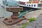 Rusty bollard with mooring line leading to a ship alongside the pier and modern buildings in the background, Bremerhaven fishing p