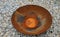 Rusty bowl with drain shaped like a big plate. The bowl stands on a gravel surface. The place serves as a fireplace neo barbecue p