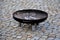 Rusty bowl with drain shaped like a big plate. The bowl stands on a gravel surface. The place serves as a fireplace neo barbecue p