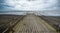 Rusty bridge stretching into the lifeless sea, Caspian sea under blue sky in early September, snag on the beach