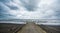 Rusty bridge stretching into the lifeless sea, Caspian sea under blue sky in early September, snag on the beach