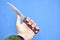 Rusty criminal sharp knife in hand on a blue background